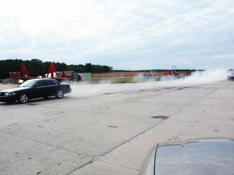 2001 Mercury Grand Marquis - A black 2001 Mercury Grand Marquis performs a burnout on a track, kicking up smoke.