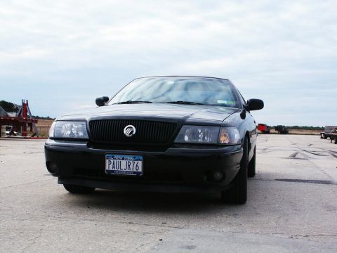 2001 Mercury Grand Marquis - A black sedan is parked outdoors on a paved surface under a cloudy sky.