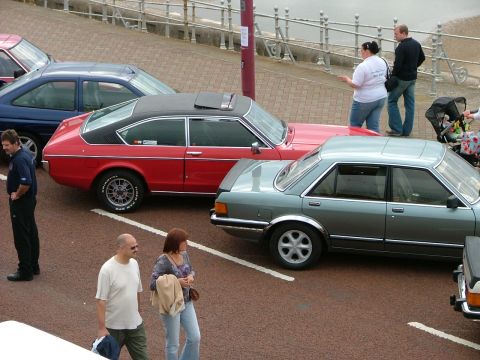 2001 Ford Fiesta - Two cars are parked next to each other on a paved surface, with people nearby.