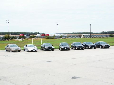 2001 Mercury Grand Marquis - A lineup of sedans, including a silver Mercury Grand Marquis and several black sedans, are parked outdoors.