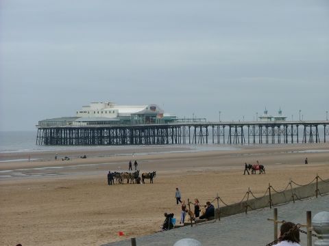 2001 Ford Fiesta - A wide view of a beach with a pier in the background and people enjoying the day.