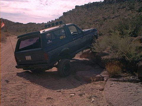 1987 Ford Bronco - This 1987 Ford Bronco navigates a challenging off-road course with rocky terrain and dusty paths.