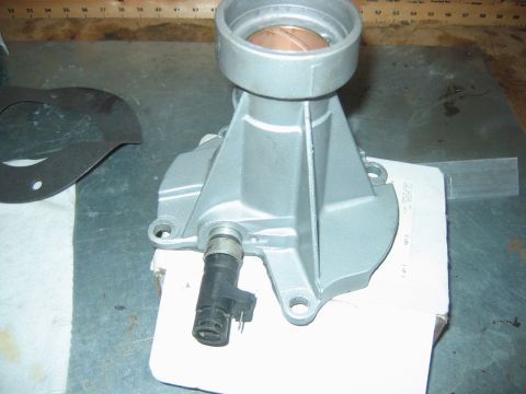 1992 Ford Bronco - A cast-aluminum transmission extension housing sits on a metal workbench, showing a bronze bushing inside the output bore and a black elect…
