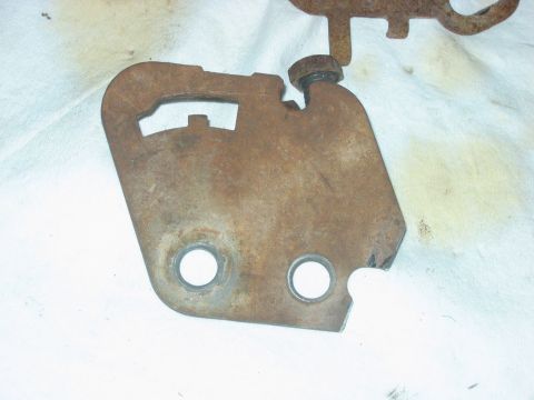 1992 Ford Bronco - A rust-covered stamped-steel mounting bracket laid on a stained white towel, showing two large bolt holes at the bottom, slotted cutouts al…