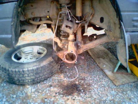 1996 Jeep Grand Cherokee - The front wheel assembly is disassembled, showing the brake caliper and suspension components.