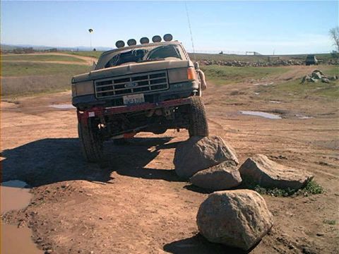 1987 Ford Bronco - This truck is navigating a rocky, off-road course with a clear blue sky overhead.