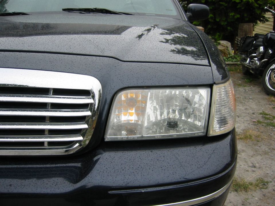 Dark blue sedan's chrome grille and headlight assembly, 1998 model year suggested by grille design