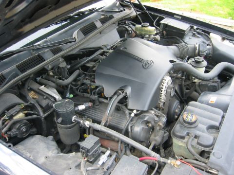 1999 Ford Crown Victoria - The engine compartment of a car is shown, with the hood open, revealing the engine and its components.