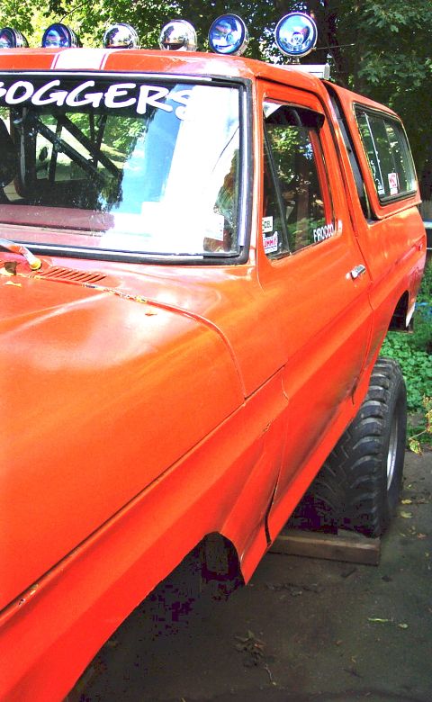 1978 Ford Bronco - Orange 1978 Ford Bronco with "FOGGERS" decal on windshield and auxiliary lights on the roof.