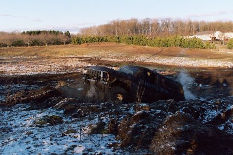 1979 Ford Bronco - A 1979 Ford Bronco is stuck in a muddy and snowy area, with steam rising from the engine.