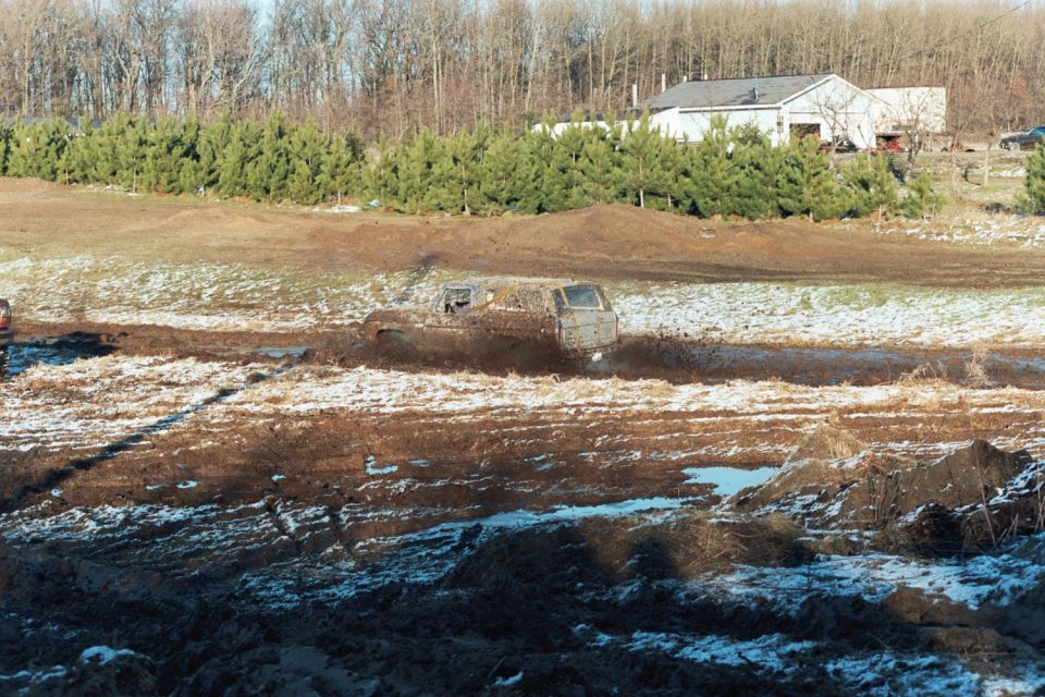 off-road vehicle stuck deep in mud, another vehicle visible to the left