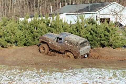 1979 Ford Bronco - Muddy 1979 Ford Bronco stuck in a muddy ditch during an outdoor event.
