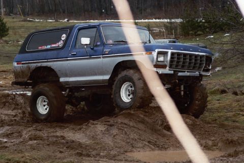 1979 Ford Bronco - A lifted Ford Bronco navigates a muddy terrain during an outdoor event.