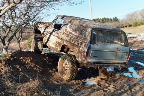 1979 Ford Bronco - This heavily mud-caked 1979 Ford Bronco navigates a challenging off-road terrain during a winter event.