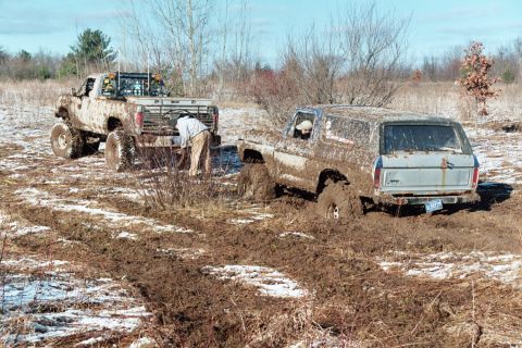 1979 Ford Bronco - Two off-road vehicles are stuck deep in the mud during an outdoor excursion.