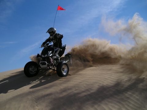 1993 Ford Bronco - Rider on a quad bike creates a large dust cloud while riding on a sand dune.