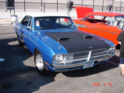 1987 Ford Bronco - A blue Dodge Dart with a black hood and white roof is parked next to an orange classic car.