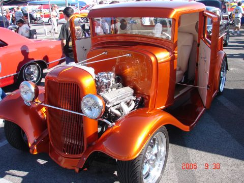 1987 Ford Bronco - A custom hot rod with a shiny orange paint job and a powerful engine is displayed at an outdoor event.