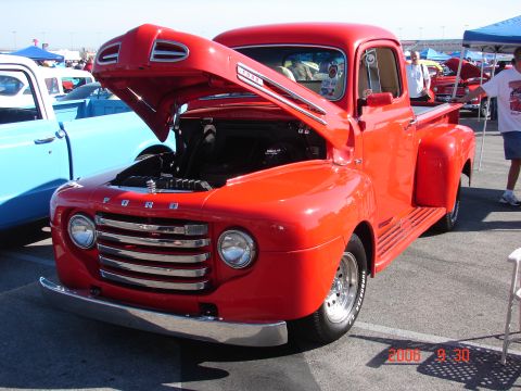 1987 Ford Bronco - A classic red Ford pickup truck is displayed with its hood open at an outdoor event.