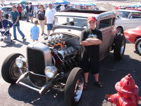 1987 Ford Bronco - Boy poses with a custom hot rod at an outdoor car show.