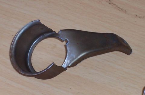 1978 Ford Bronco - A damaged metal bracket, possibly a component from a vehicle, is shown against a wooden background.