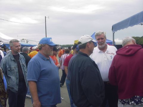 1990 Ford Mustang - People mingling at an outdoor event under a cloudy sky.