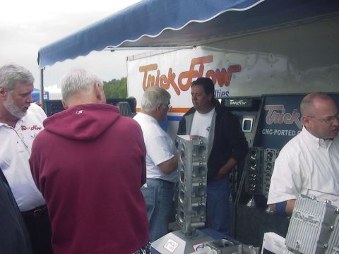 1990 Ford Mustang - Engine parts, including a V8 engine block and cylinder heads, are displayed under a tent with 'Trick Flow' branding visible.