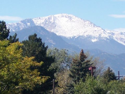 1972 Ford Ranchero - A mountain range with snow on its peaks is seen through trees on a clear day.