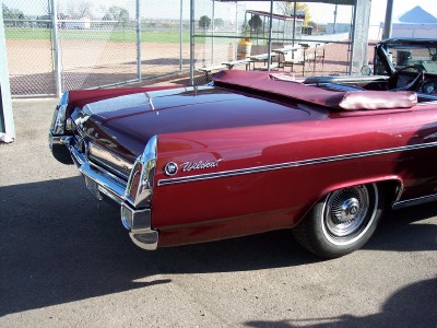 1972 Ford Ranchero - Rear view of a red 1967 Wildcat convertible parked outdoors near a baseball field.