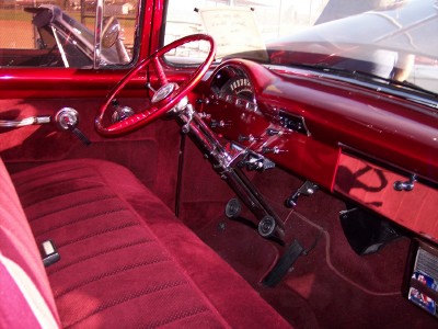 1972 Ford Ranchero - The interior of a classic car features a red bench seat and a shiny red dashboard with a speedometer.