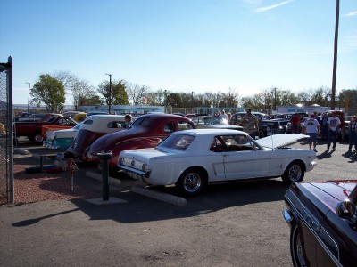 1972 Ford Ranchero - A white 1965 Ford Mustang coupe is parked with its hood open at an outdoor car show, alongside other vehicles.