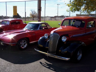 1972 Ford Ranchero - Three red vehicles are parked in a line on a sunny day, with a fence and field in the background.