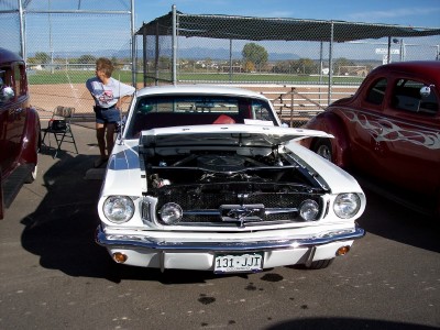 1972 Ford Ranchero - A white 1965 Ford Mustang coupe is displayed with its hood open, parked next to a red custom car.