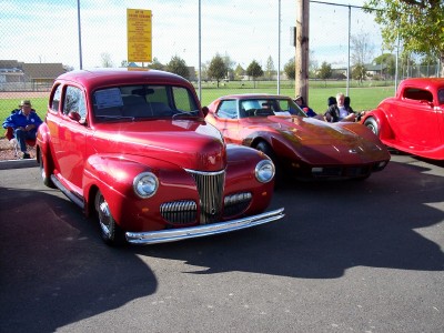 1972 Ford Ranchero - Three red vehicles are parked outdoors, with a sedan in the foreground and a sports car behind it.