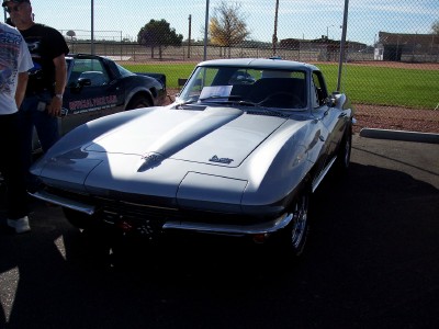 1972 Ford Ranchero - Silver 1965 Corvette Sting Ray coupe is the main subject, with other vehicles and people visible.