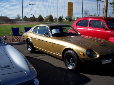 1972 Ford Ranchero - A gold Datsun 280Z is parked at an outdoor event with other vehicles nearby.