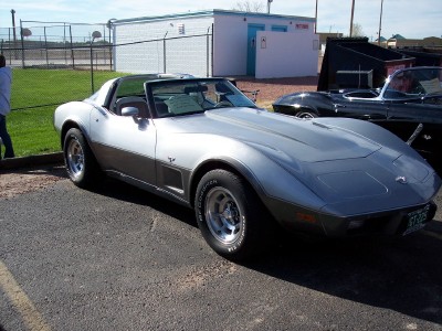 1972 Ford Ranchero - A two-tone Chevrolet Corvette is parked outdoors next to another vehicle.