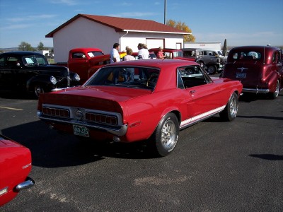 1972 Ford Ranchero - Rear view of a red 1967 Ford Mustang coupe with a white side stripe.