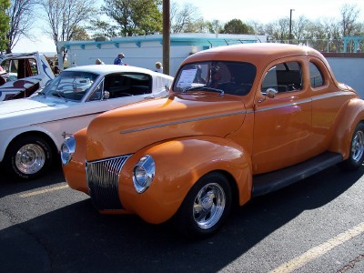 1972 Ford Ranchero - An orange coupe from the 1940s is parked next to a white vehicle.