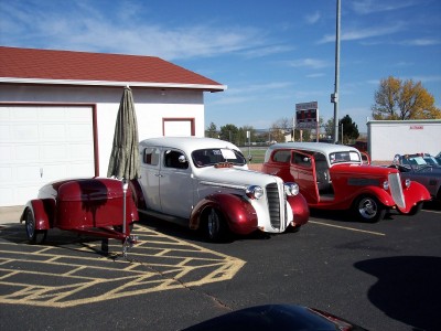 1972 Ford Ranchero - A white and red sedan with a matching trailer is parked next to a red hot rod and another vehicle.
