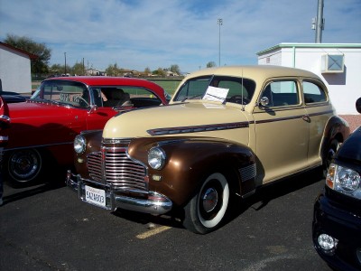 1972 Ford Ranchero - A two-tone tan and brown sedan from 1941 is parked next to a red car and a black vehicle.