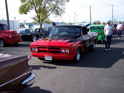 1972 Ford Ranchero - A red and black pickup truck with flame graphics on the hood is parked at an outdoor event. The license plate reads "67 BSS 101".