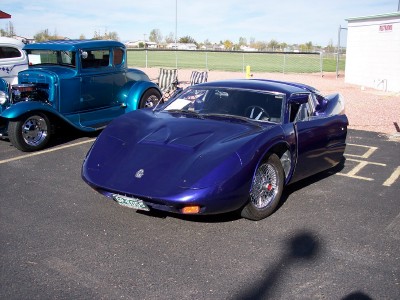 1972 Ford Ranchero - A custom purple sports car is parked next to a blue hot rod at an outdoor event.