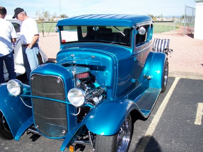 1972 Ford Ranchero - A bright blue hot rod coupe is parked in a lot, its custom engine and classic body style.