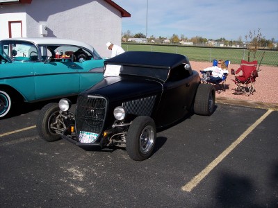 1972 Ford Ranchero - A black hot rod is parked next to a teal and white classic car at an outdoor event.
