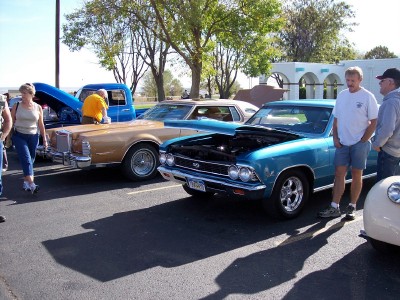 1972 Ford Ranchero - Several classic cars are parked in a lot, with people admiring them.