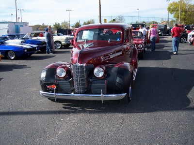 1972 Ford Ranchero - A classic maroon and black sedan is displayed at an outdoor event with other vehicles in the background.