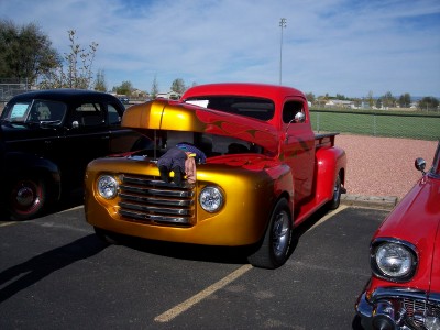 1972 Ford Ranchero - A custom red and gold pickup truck is displayed with its hood open, parked next to other vehicles.