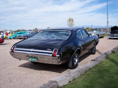 1972 Ford Ranchero - Rear view of a black 1969 Oldsmobile Cutlass at an outdoor car event.