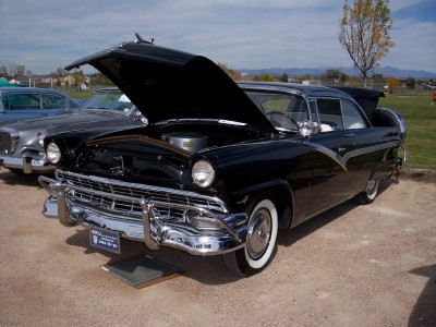 1972 Ford Ranchero - A black 1955 Ford Fairlane Crown Victoria is displayed with its hood open, parked next to another vehicle.